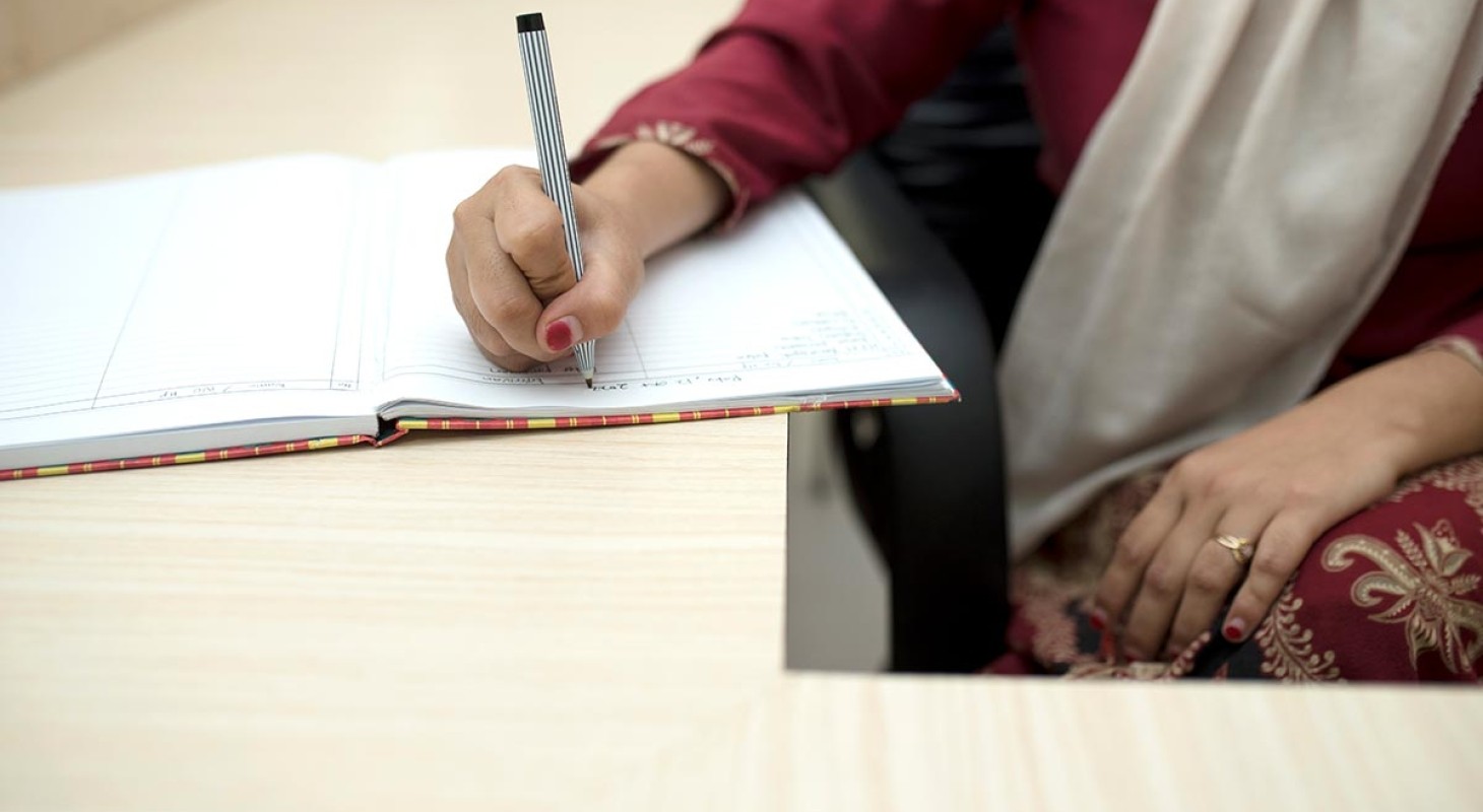 woman in sari writing in a book