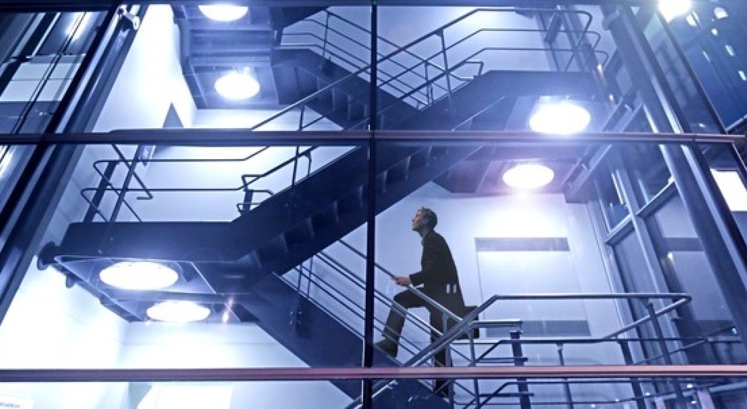 man climbing stairs in glass high rise building at night