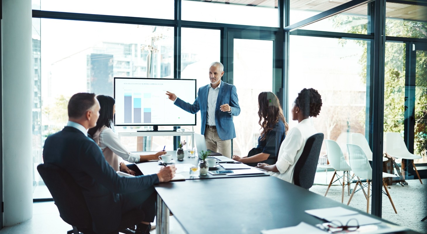 man giving presentation to group of people in glass room