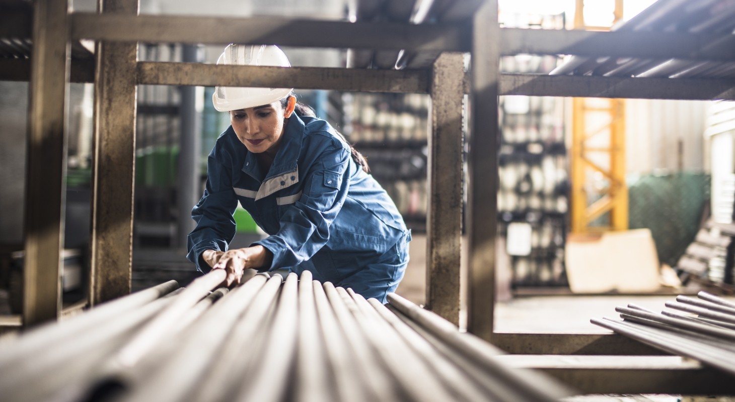 female steelworker in hardhat moving poles