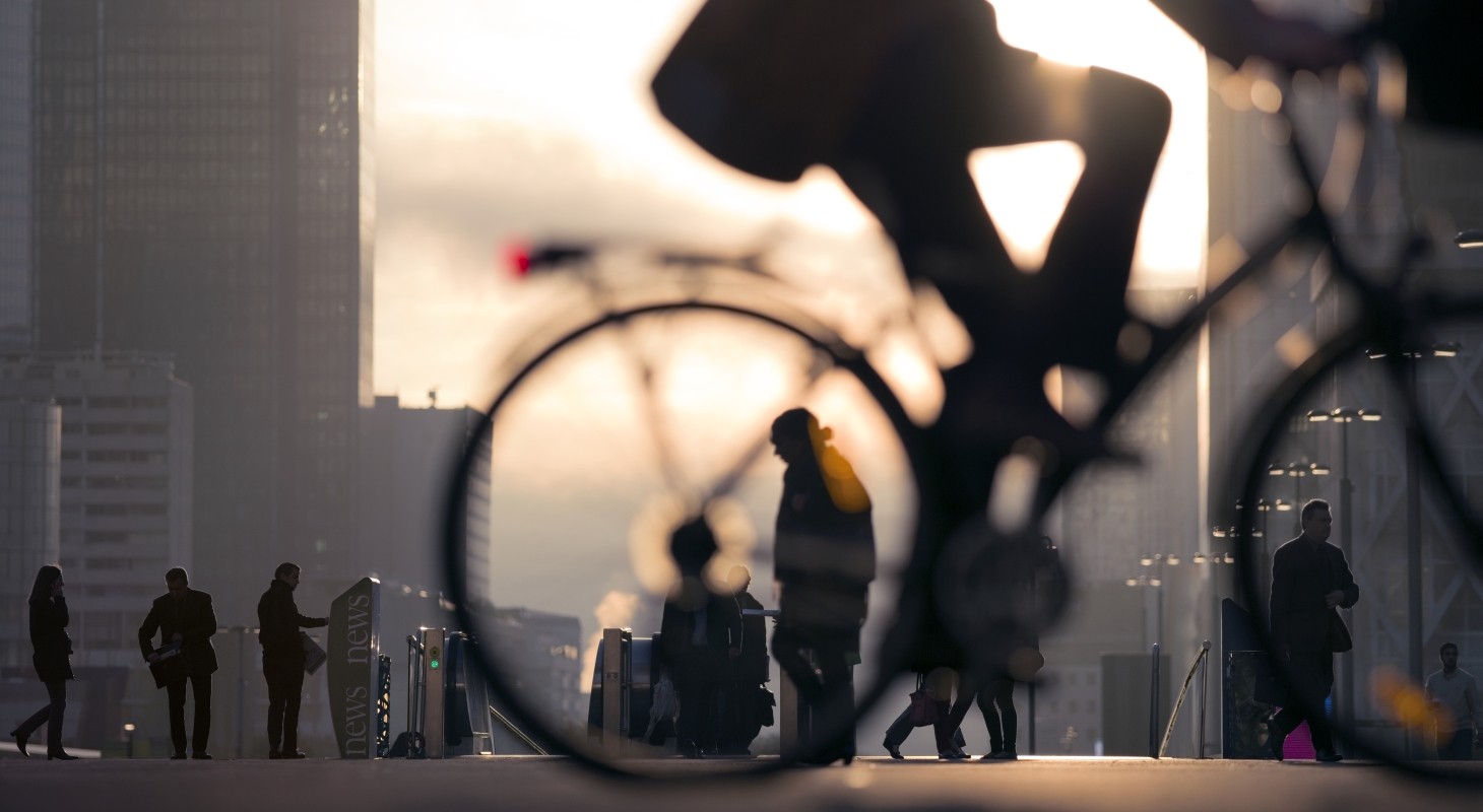 Silhouette of business person on bicycle on busy street