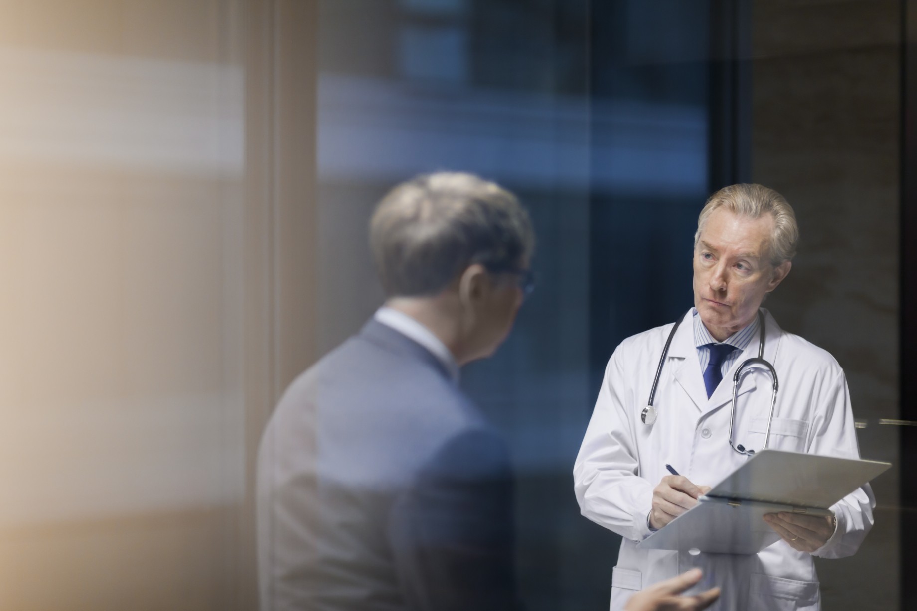 doctor with businessman taking notes in office