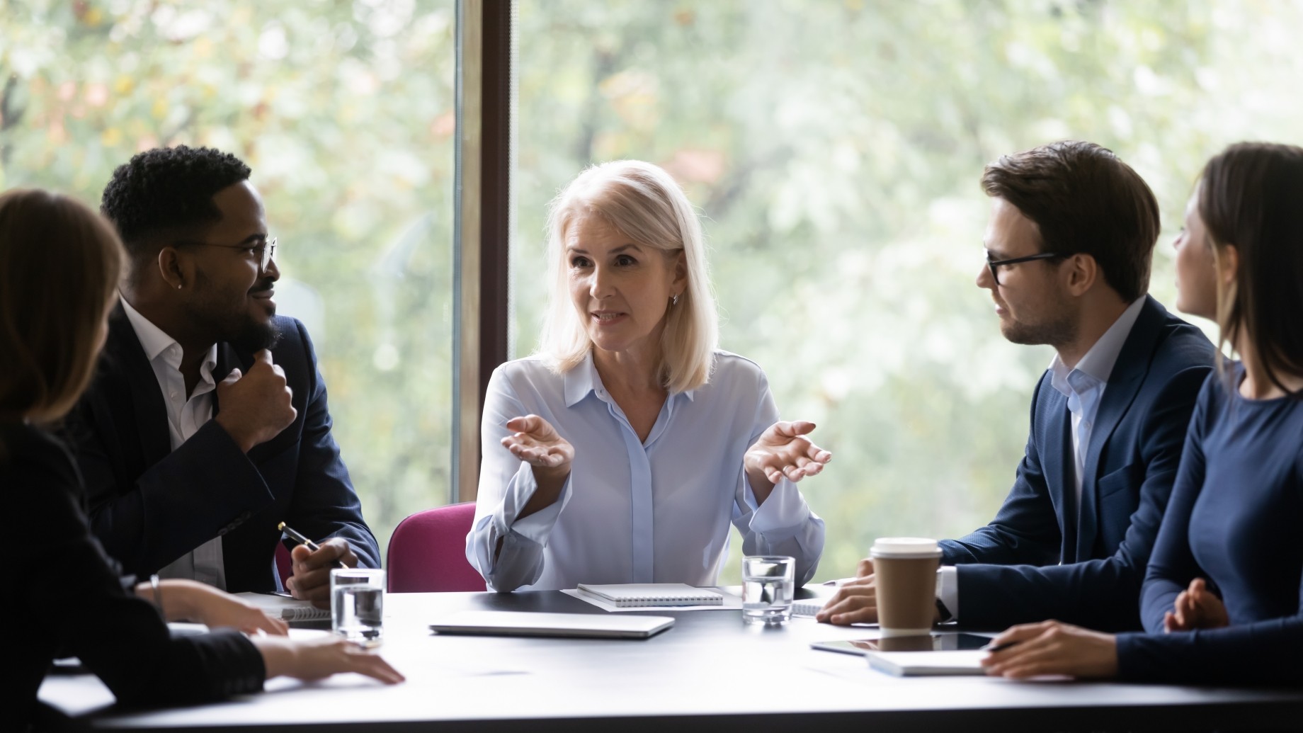 mature leader giving helpful information to young diverse professionals