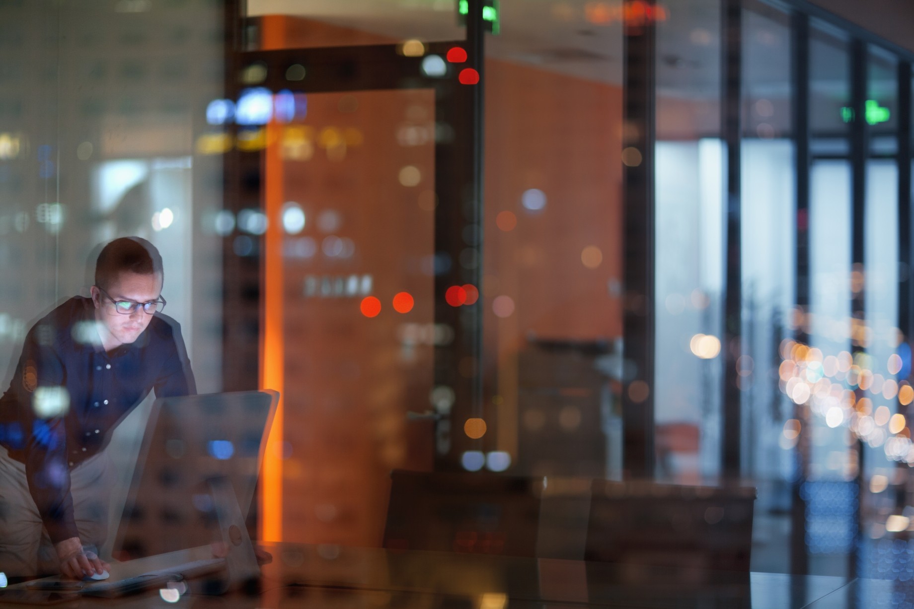 young man looking at computer in office at night