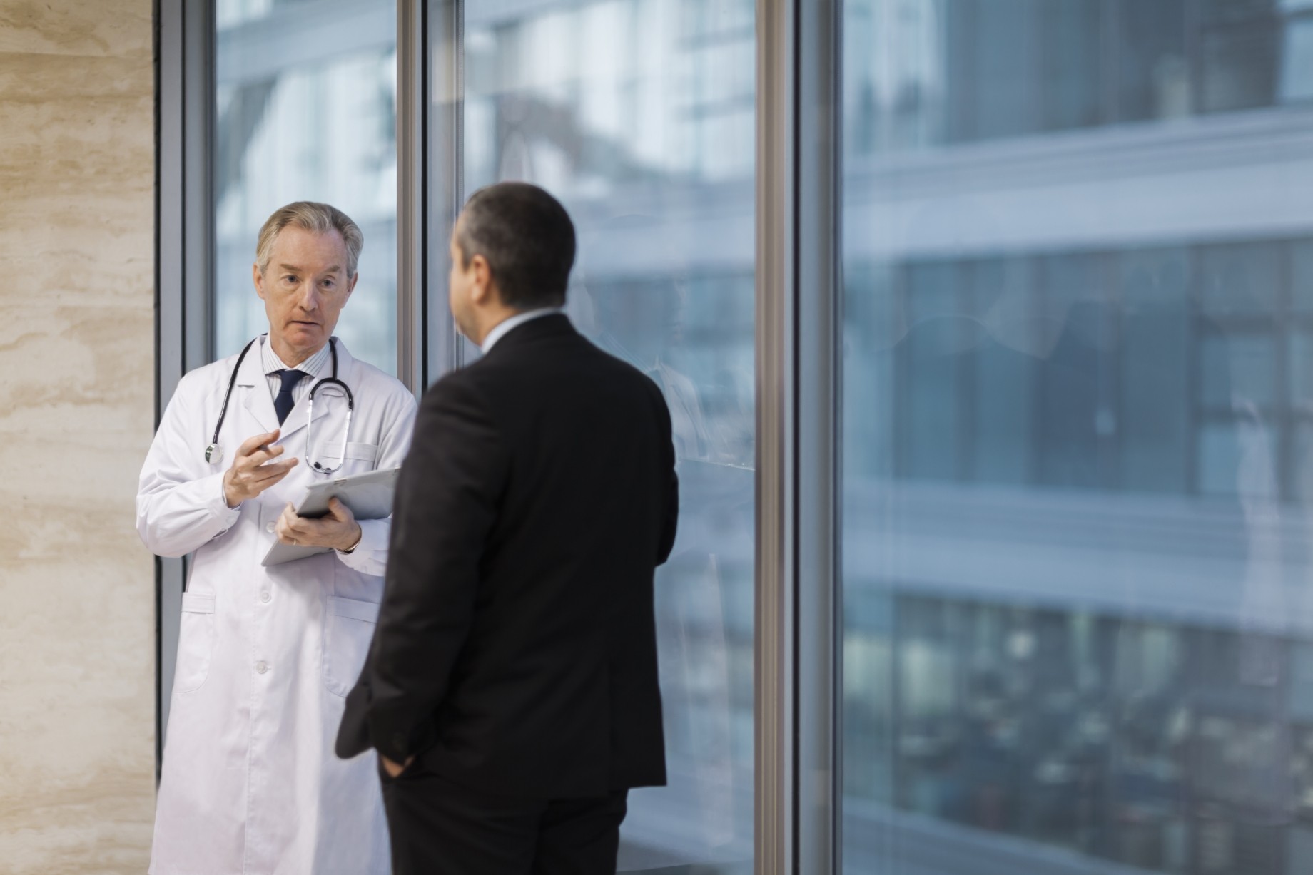 doctor talking with businessman in hallway