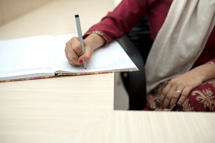 woman in sari writing in a book