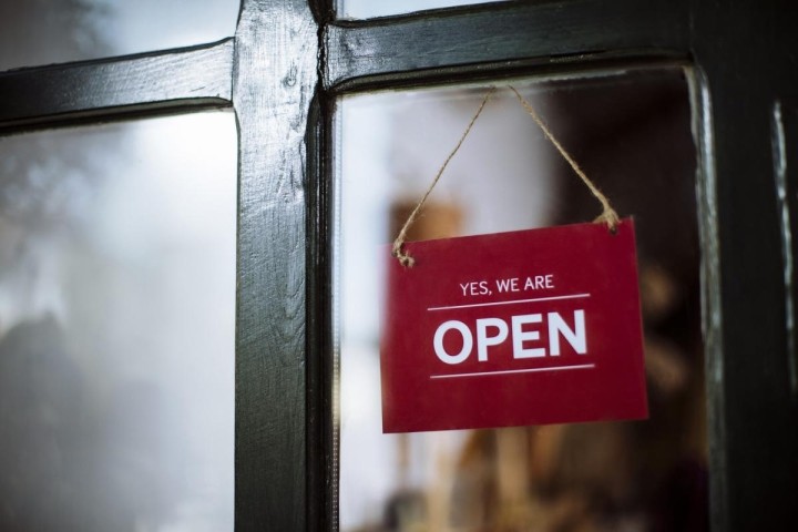 red sign hanging in window that says yes we are open