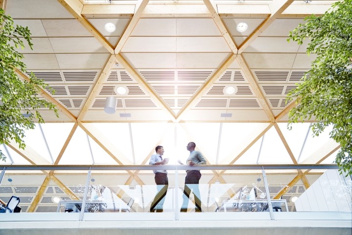 two male colleagues standing at glass railing in modern office