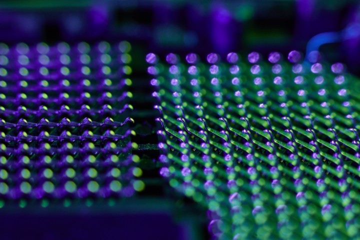 extreme closeup of cpu land grid array lit with purple and green lights