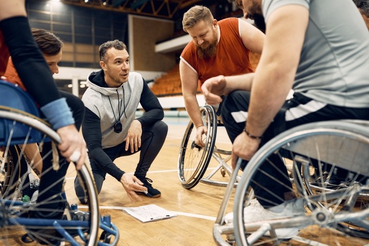 coach of basketball team talking with his players in wheelchairs