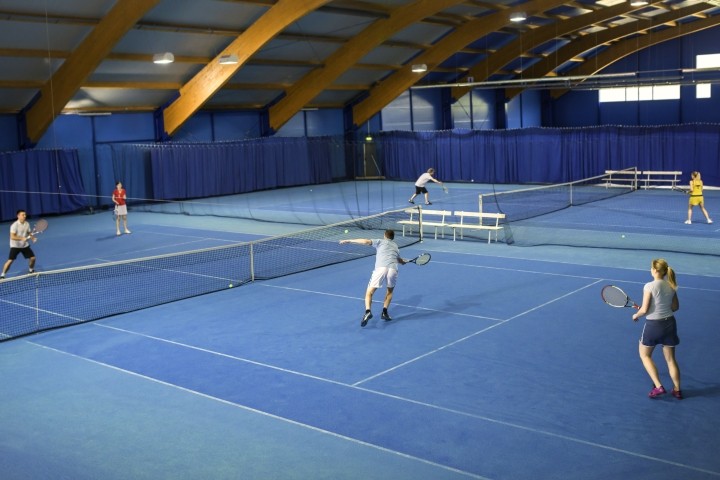 indoor game of mixed doubles tennis on light blue court