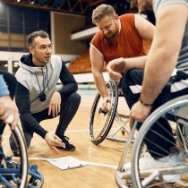 coach of basketball team talking with his players in wheelchairs