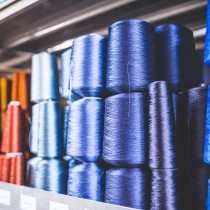 orange red blue and purple spools of thread stacked on shelf