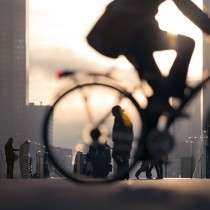 Silhouette of business person on bicycle on busy street