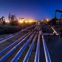 multiple pumpjacks illuminated against evening sky