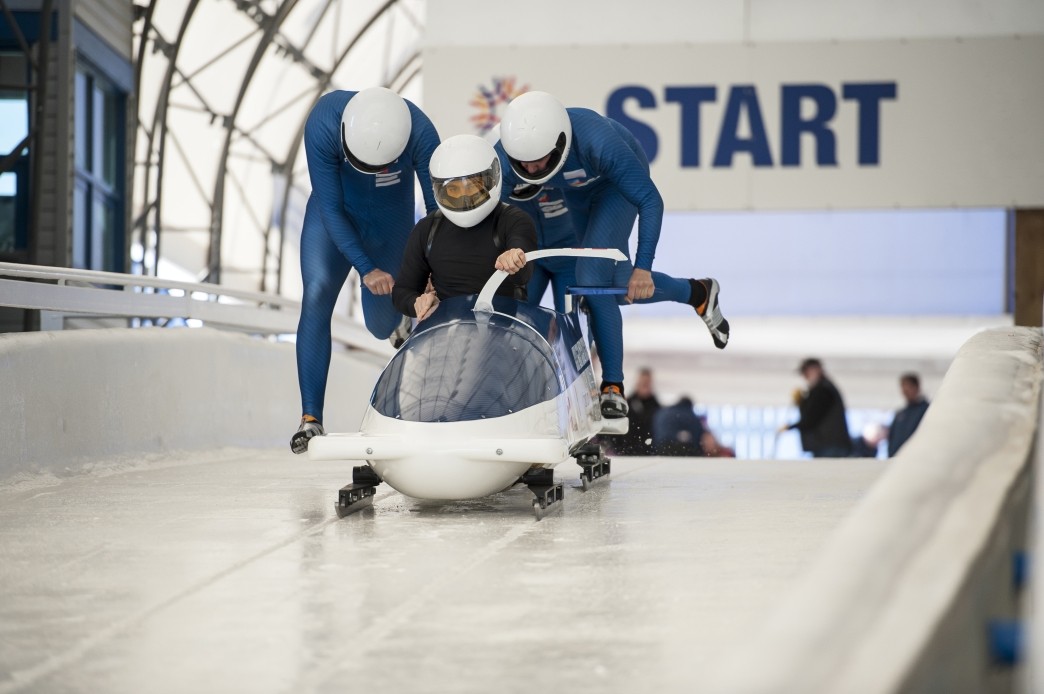 bobsledders push bobsled out of start gate