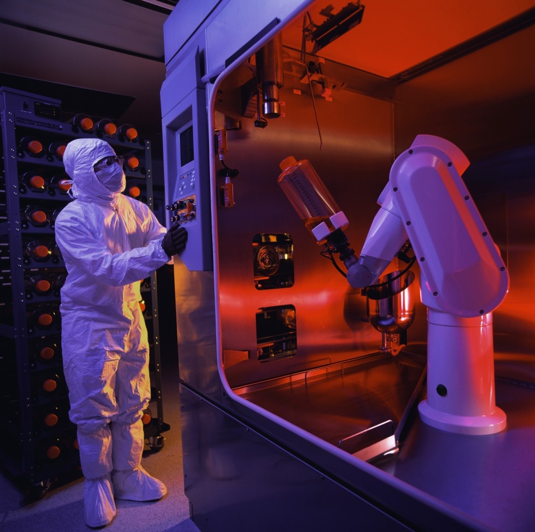 biotech worker in clean room with robotic arm